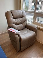 Front-left angle view showing chair frame, upholstery, remote on armrest and manual on seat