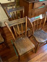 Four wooden arrow back chairs, visible surface wear and damage including a broken slat on one chair with the piece included for repair.