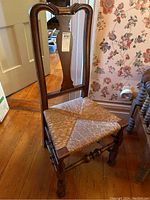 Full view of wooden chair showing tall backrest and rush seat, highlighting overall condition and design.