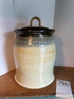 Front view of Terry Pottery crock with lid, showing speckled beige and dark brown glazed body and lid with handle.