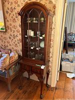 Full front view of the cabinet showing arched top, glass door and two lower drawers