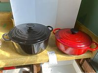 Both red and black cast iron pots with lids displayed on counter
