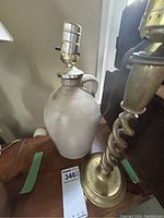 Photo of one handcrafted table lamp with a large crock base and brass twisted candle holder fixure on top, showing the socket and switch.