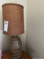 Full view of lamp showing marbled ceramic base and cylindrical woven fabric shade