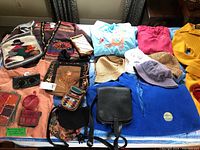 Wide shot of various clothing, bags, hats, and small accessories laid out on a bed.