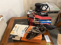 Lot showing Black & Decker and Skil sanders with wood planes and sanding belts on table, including boxes and manuals.