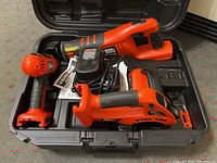 Power tools in an open case including Black & Decker cordless reciprocating saw, circular saw, drill, battery, and charger.