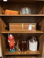 View of all items arranged on wood shelving including the oak box, wood box, glass bowl, Beefeater figurine, and jugs.