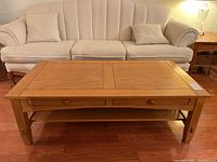 Front view of coffee table showing top surface and drawers with sofa in background