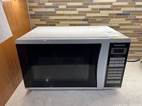 Front view of white Panasonic microwave oven with black glass door, control panel visible.