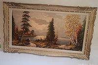 Full view of the oil painting showing a lake landscape with trees and ornate beige and gold frame.
