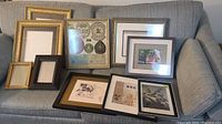 Multiple framed items arranged on a couch, including framed badge display and various prints
