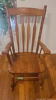 Front view of wooden rocking chair showing backrest with five vertical spindles and armrests