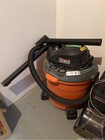 Side view of the Ridgid shop vacuum with attached hose and accessories.
