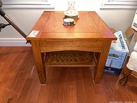Front view of wood side table showing top surface, legs, and lower shelf with items on top removed or included for scale.