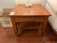 Front view of wood side table with pull-out panel on top and lower shelf under.