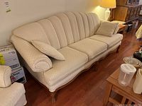 Front left-angled view showing full sofa with two pillows, upholstery and leg style