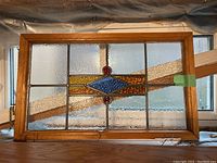Full front view of one framed stained glass panel leaning against a window