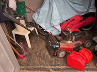 Full view of red Toro mower and two red jerry cans inside shed