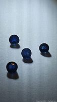 Five round cut blue sapphire gemstones on a white background illuminated to highlight facets and color.