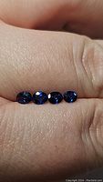 Four oval cut natural sapphires arranged on finger showing deep royal blue color and clarity.