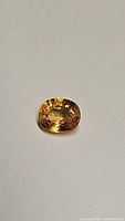 Close up image of oval golden yellow sapphire gemstone showing faceted surface and clarity