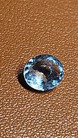 Clear photo showing aquamarine gemstone oval flower cut on a brown textured background highlighting natural lagoon blue color and clarity.