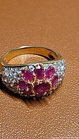 Close-up of the front side of the ruby and white topaz cluster ring showing ruby arrangement and topaz pave stones on band