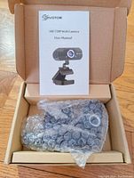 Photo of the webcam wrapped in bubble wrap inside the box with user manual included.