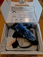 Opened original box showing black headset with two sets of ears, white with light pink and white with blue and black fur.