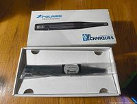 Original box labeled Polaris Intraoral Camera with the black intraoral camera inside a plastic sleeve.