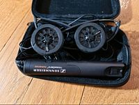 Headset folded inside black zippered case, showing missing ear pads exposing speaker interiors