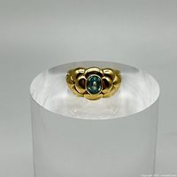 Front view showing oval green gemstone and surrounding petal motif