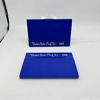 Two blue sleeves for United States Proof Sets dated 1968 and 1970 respectively, showing the fronts with printed year and title.