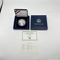 Photo showing the coin in its blue United States Mint presentation case with the certificate of authenticity placed below.