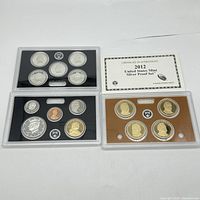 Three sets of United States Mint coins with certificate of authenticity displayed side by side on white background