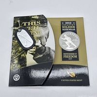 Front view of the coin in packaging with attached dog tag showing infantry soldier design and packaging text.