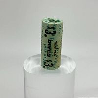 Front view of the rolled bundle showing clear text '$3 Dimes' and 'Play at Harrah's' on green printed paper wrapper