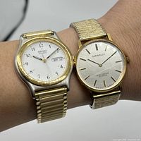 Two men's wristwatches worn on wrist, showing watch faces and bands.