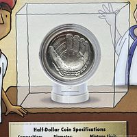 Front view of the curved baseball glove half-dollar coin in clear capsule display case mounted in the original packaging, showing the coin's shape and design.