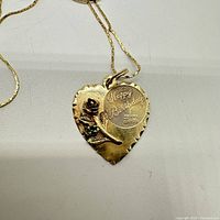 Close-up of pendant front showing engraving, rose motif, green stone