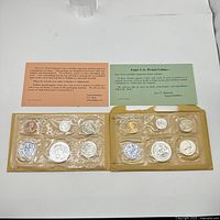 Two sealed US Philadelphia Mint sets from 1959 and 1962 with coins and informational inserts visible.