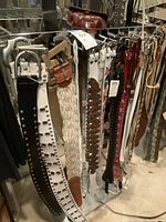 Belts hung on metal rack showing grommet and studded designs