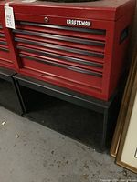 Red Craftsman toolbox on black wooden cart, front view