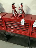Two red Craftsman 2-ton jack stands atop red tool chest on black cart