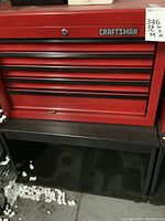 Front view of red Craftsman toolbox mounted on black wooden cart