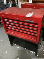 Front and top view of red Craftsman toolbox chest on black wooden cart