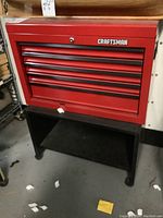 Front view of red Craftsman toolbox mounted on black wooden cart