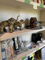 Shelf display showing two elephant figurines and a decorative vase.