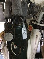 Front view of green and white Miller golf bag beside white golf bag with club head covers
